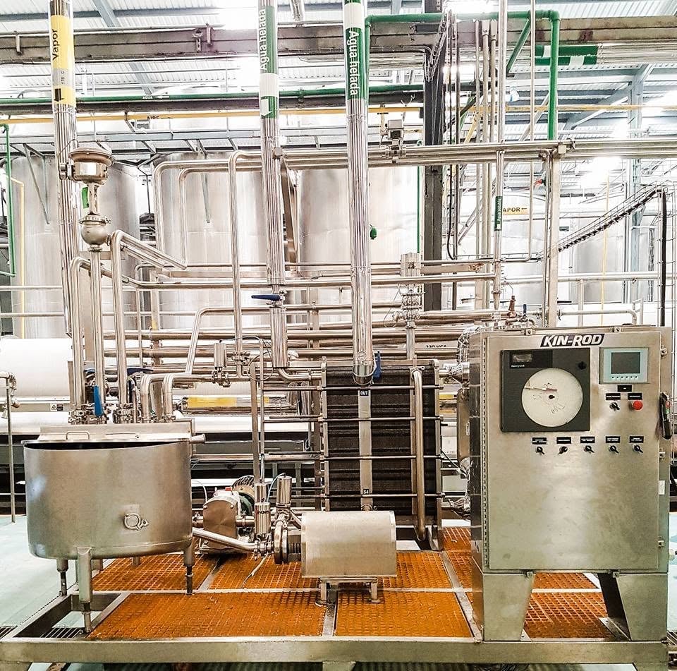Sistema de procesamiento de bebidas con tanques, tuberías y panel de control KIN-ROD instalado en planta industrial