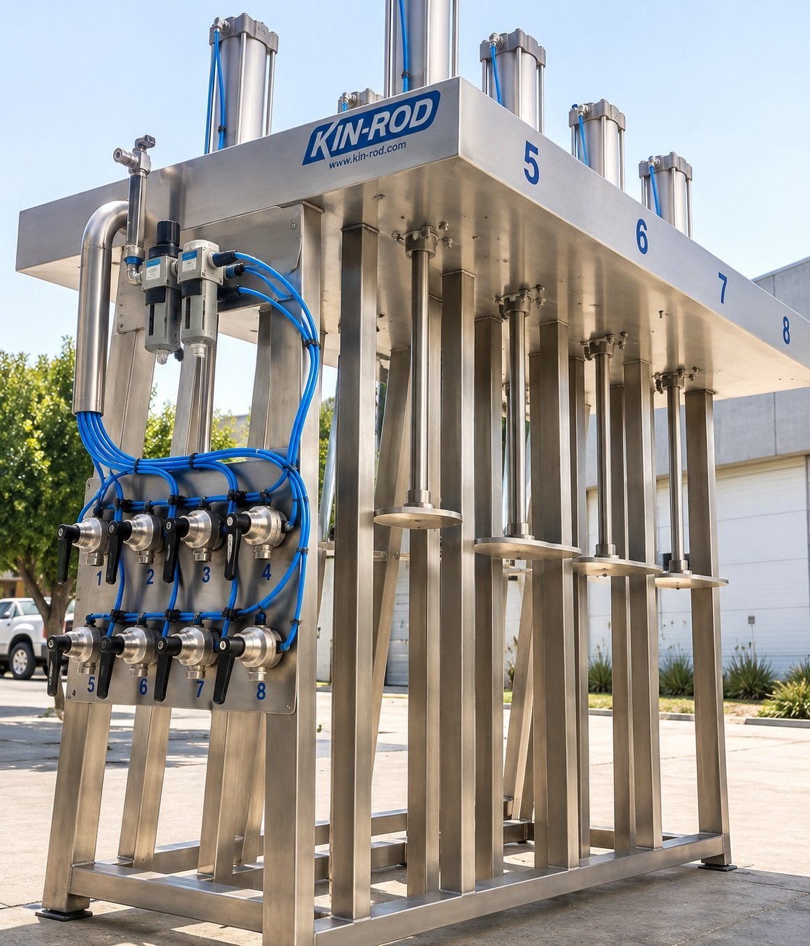 Sistema de dispensado KIN-ROD con múltiples columnas de acero inoxidable y mangueras azules en exhibición al exterior