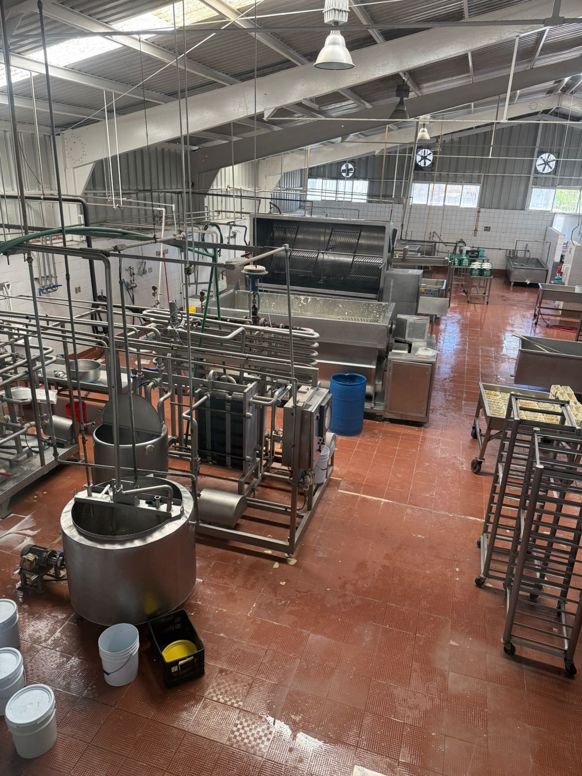 Nave industrial KIN-ROD con piso rojo, líneas de proceso de acero inoxidable, tubería, tanques y equipo instalado en planta de la industria alimentaria