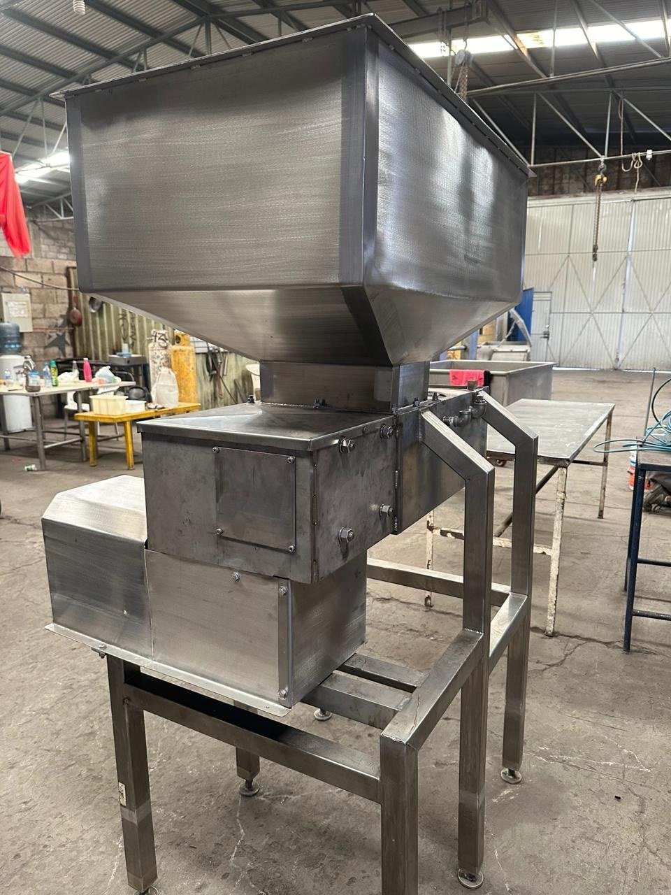 Tolva del extrusor KIN-ROD en acero inoxidable T304 montada sobre estructura de soporte con mecanismo de extrusión integrado en taller