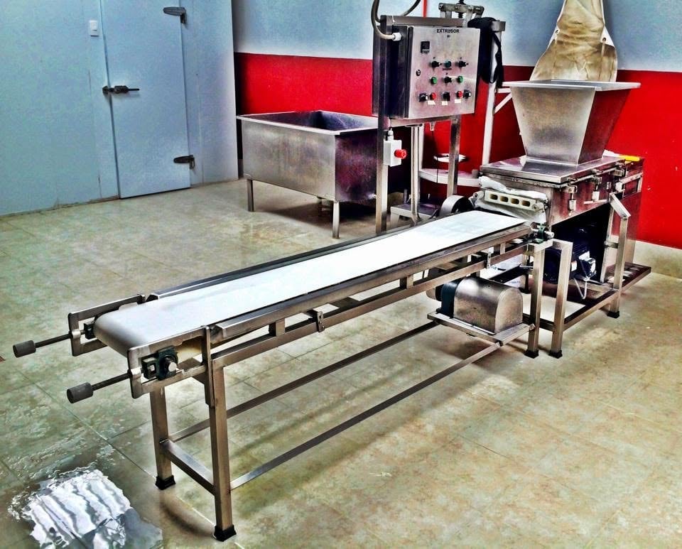 Extrusor KIN-ROD con banda transportadora de acero inoxidable en planta de proceso