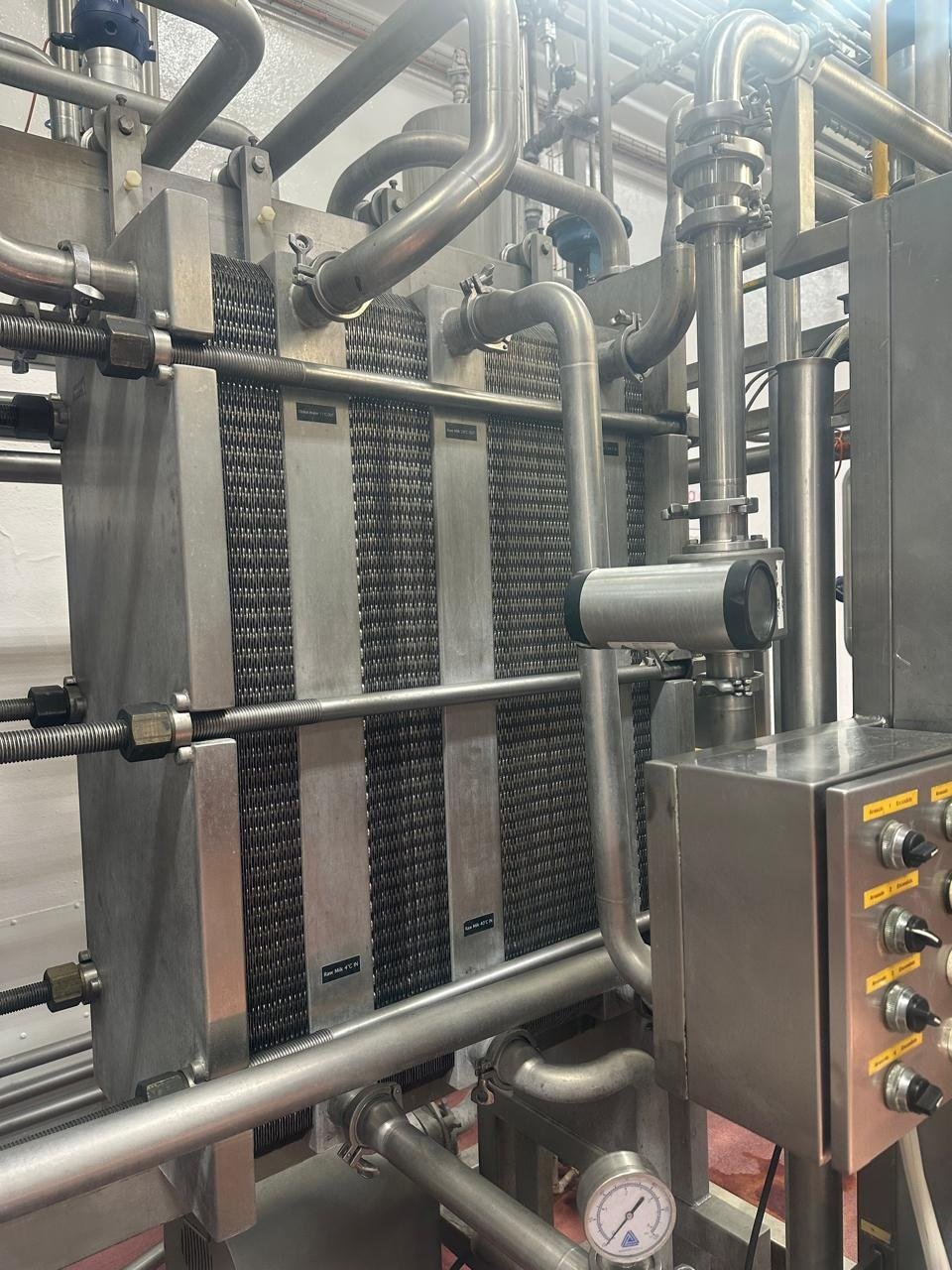 Intercambiador de calor de placas KIN-ROD con manifolds de acero inoxidable, manómetro, conexiones de proceso y cableado eléctrico en instalación de pasteurización