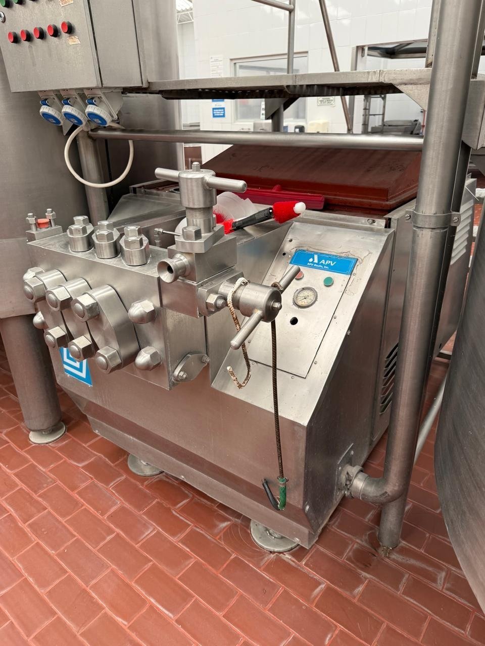 Homogenizador industrial reacondicionado por KIN-ROD con cuerpo de acero inoxidable, cabezal, conexiones de proceso y tablero de control instalados en planta