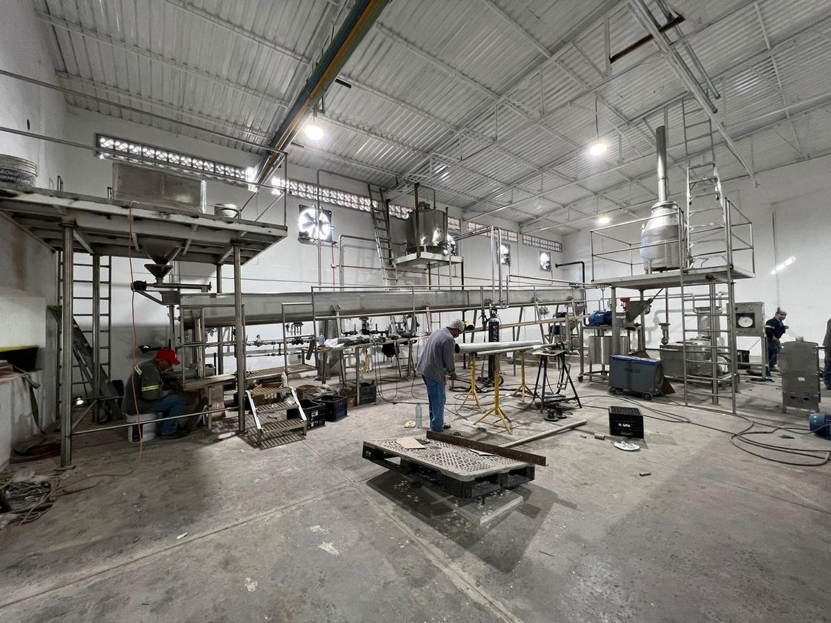 Instalación industrial KIN-ROD con equipos de acero inoxidable, tuberías, mezzanines, tanques y operadores integrando la línea de proceso en planta