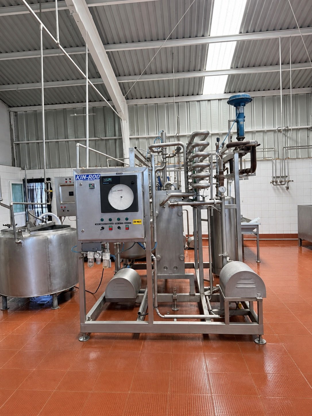 Equipo de procesamiento de leche KIN-ROD con tanque de balance, intercambiador de placas, tubería de sostenimiento y válvula diversora instalados en planta alimentaria